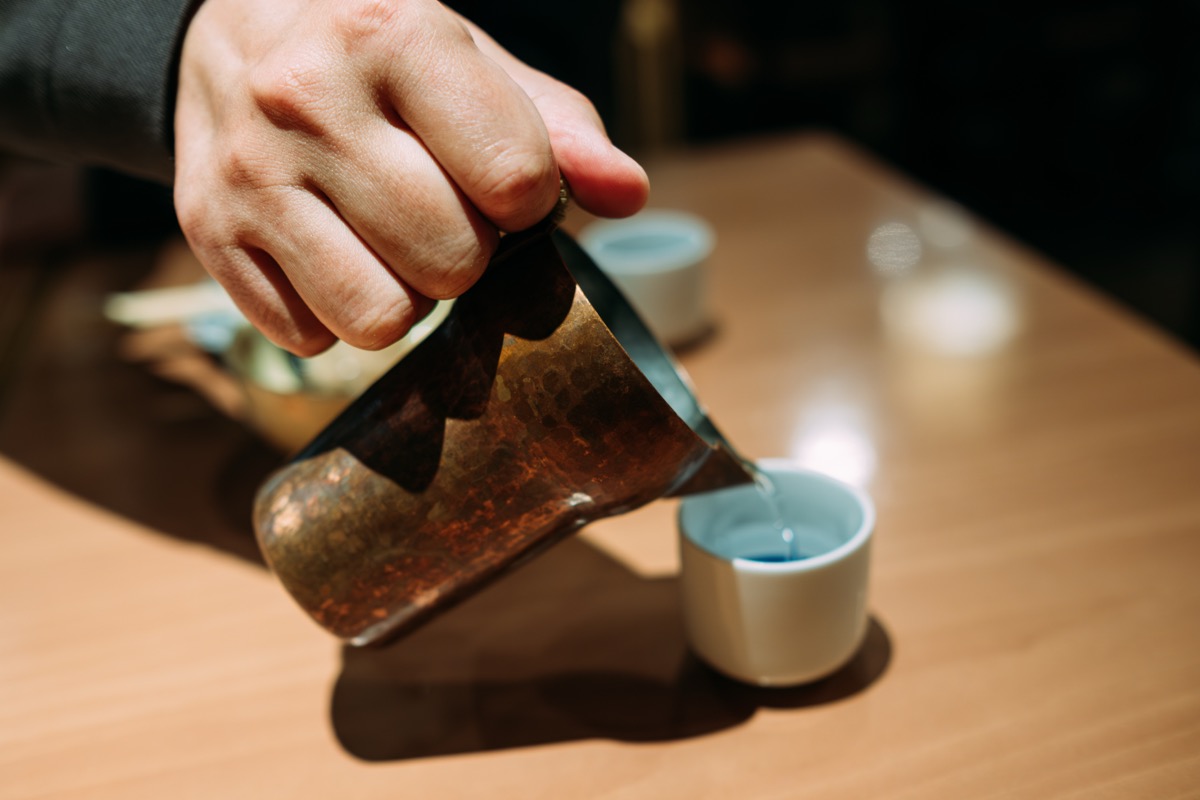 Pouring warm sake from a copper warmer